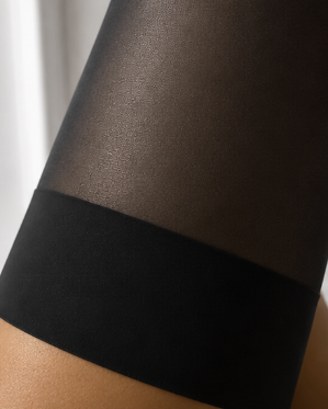 Black stockings on a person's leg against a neutral background