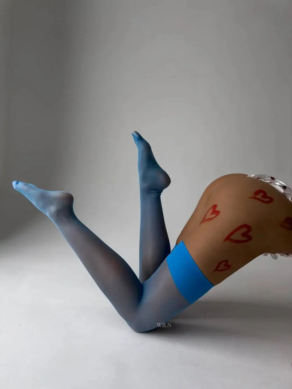 Person wearing blue tights with red heart designs on a plain background